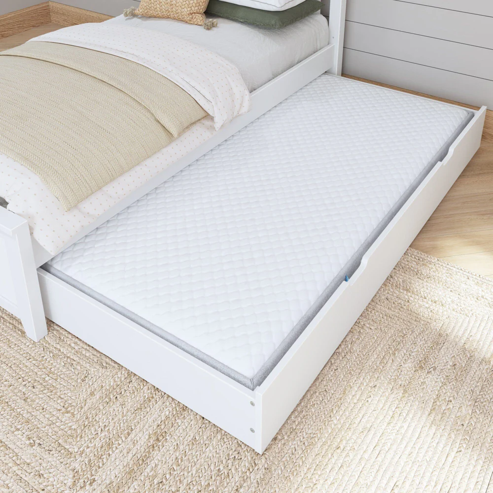 Maxtrix Trundle Bed with Slats in White - trundle pulled out from under a bed with a mattress inside, shown in a cozy bedroom on a woven rug