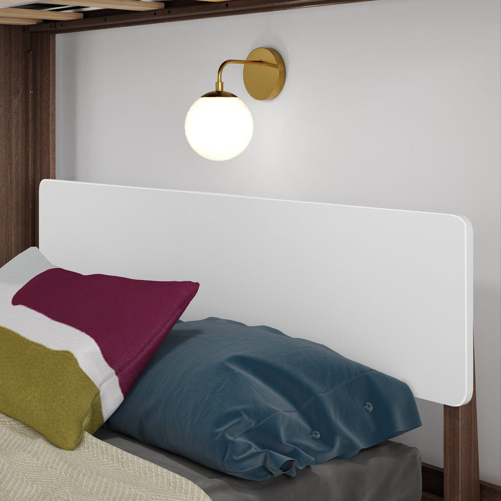 Mid-Century Modern Twin Over Full L-Shaped Bunk Bed in White/Walnut - close-up of the lower bed's white headboard panel with pillows beneath a brass wall sconce