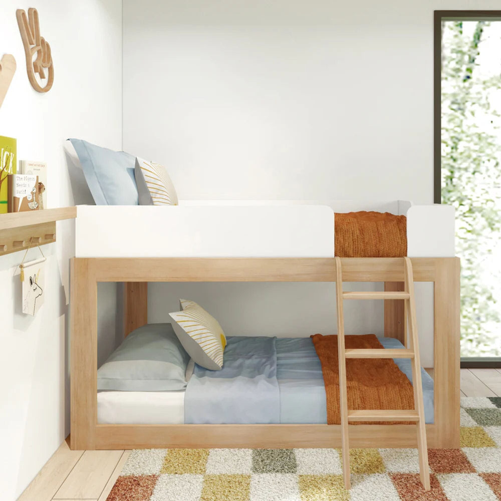 Mid-Century Modern Twin Over Twin Low Bunk Bed in White/Blonde - front view in a kids room with white guardrails on the top bunk and angled wood ladder