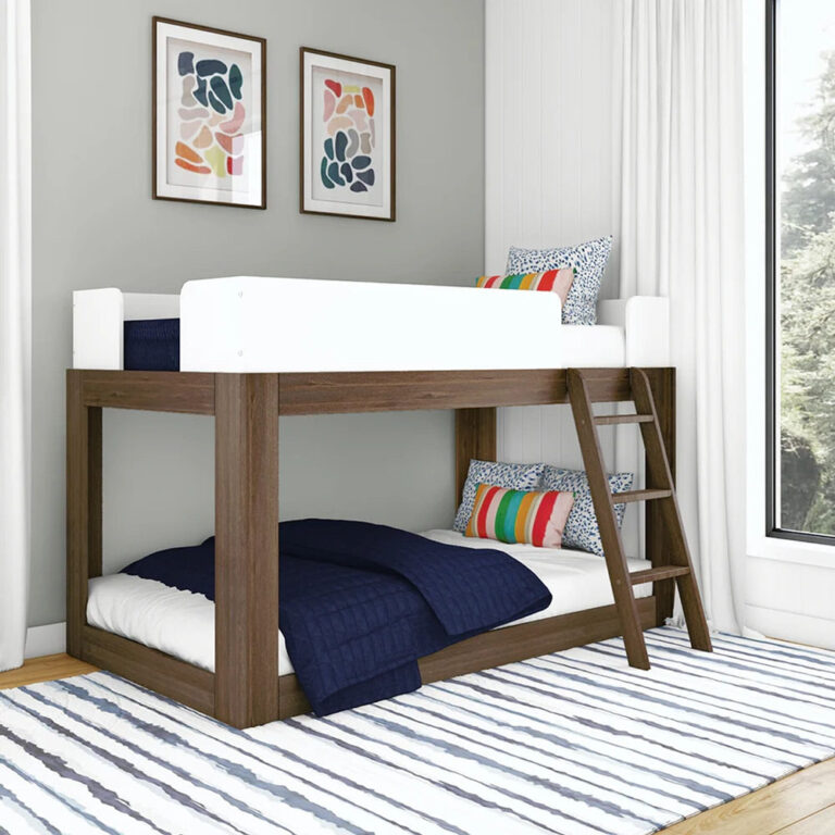 Mid-Century Modern Twin Over Twin Low Bunk Bed in White/Walnut - angled view in a kids' bedroom showing white guardrails, angled wooden ladder and low-height frame