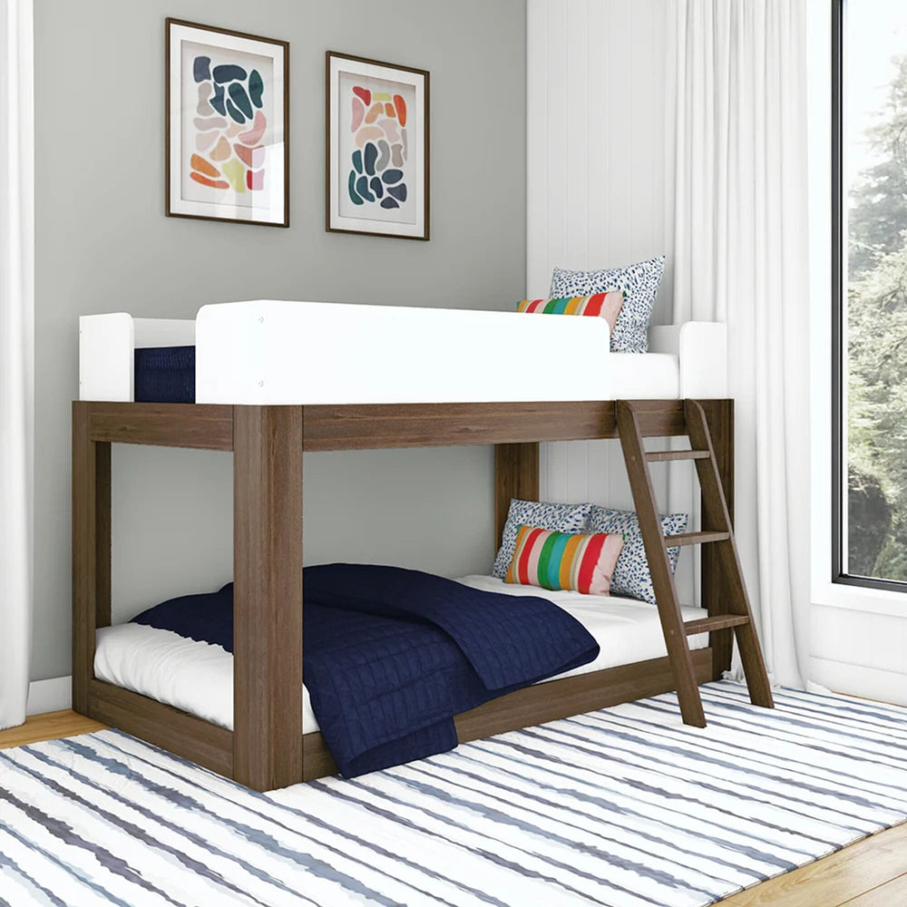 Mid-Century Modern Twin Over Twin Low Bunk Bed in White/Walnut - angled view in a kids' bedroom showing white guardrails, angled wooden ladder and low-height frame