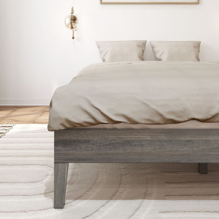 Queen Size Platform Bed Driftwood Footboard Detail Queen Size Platform Bed in Driftwood - close-up of the foot corner showing the wood-grain side rail and tapered leg beneath neutral bedding.