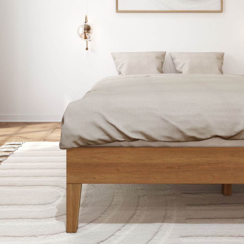 Queen Size Platform Bed Pecan Angle View Queen Size Platform Bed in Pecan - made up with a duvet and pillows in a sunlit bedroom, shown at an angle with wall sconces and framed art